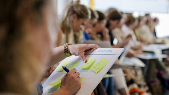 Deelnemer schrijf op een post it tijdens een workshop